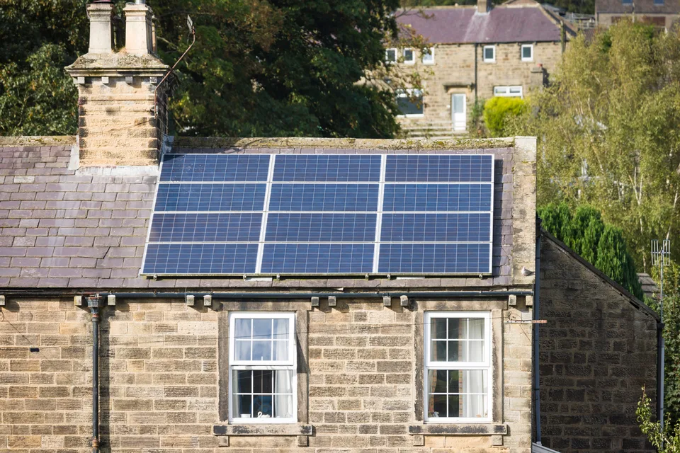 Solar panels on a stone house in Yorkshire with trees nearby.