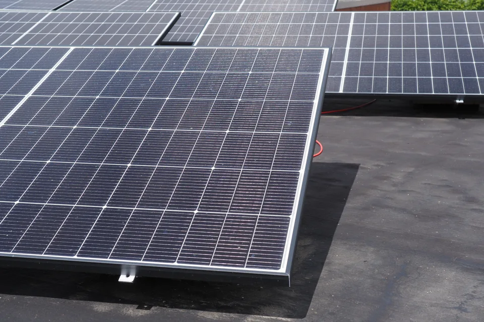 Solar panels on low angled supports on a flat garage roof.