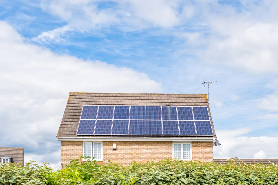 Solar panels on a residential roof beneath a cloudy sky.
