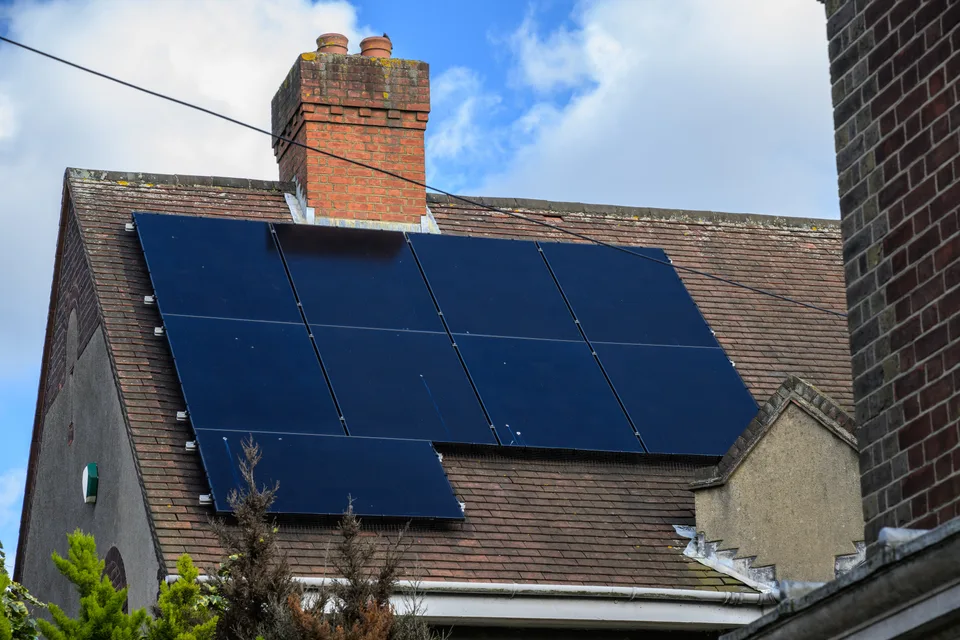 Solar panels fitted beside a chimney on a tiled house roof in the UK.